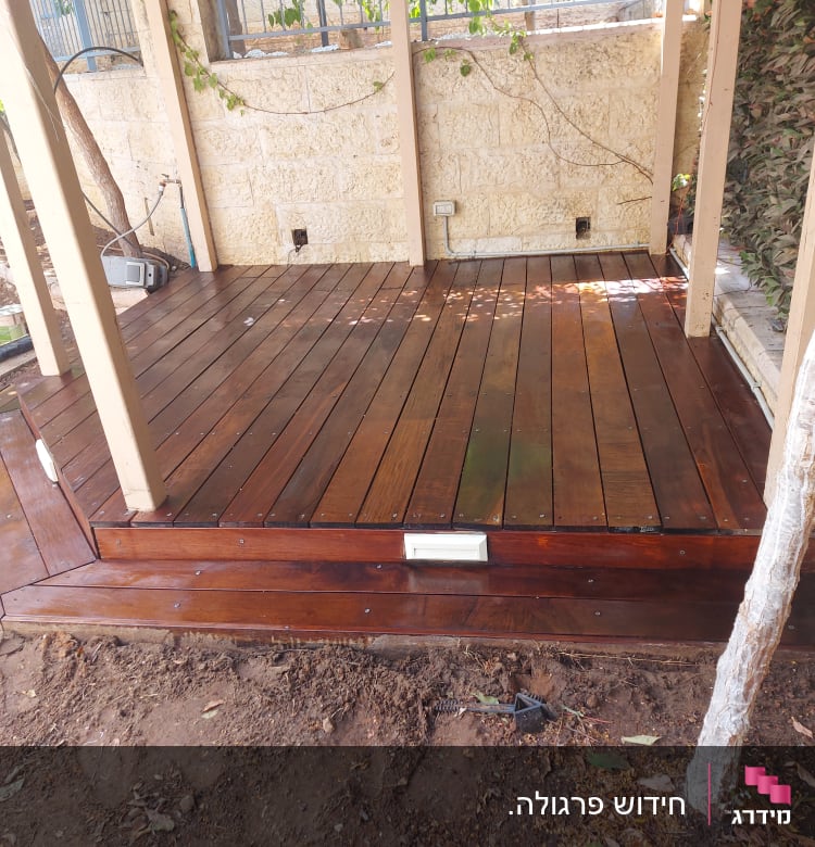 דק עץ בגינה עם עמודים וצמחייה מסביב